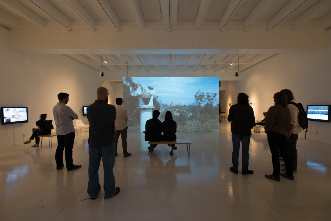 People view images on a projector in art gallery